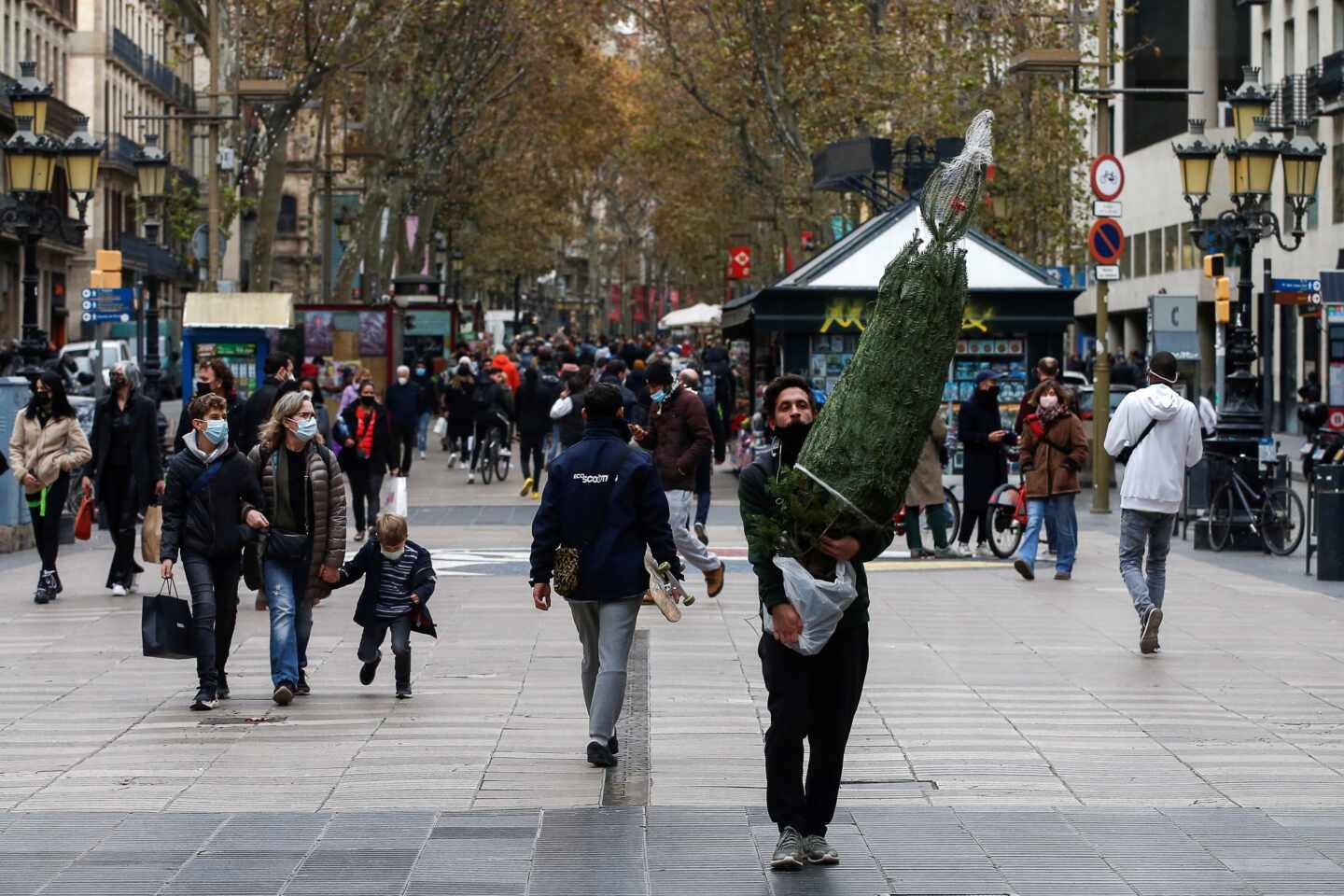 Una persona transporta un árbol de navidad por las Ramblas de Barcelona.