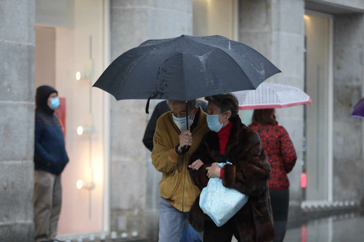 Dos personas pasean protegidas con paraguas por el centro de la capital, en Madrid.