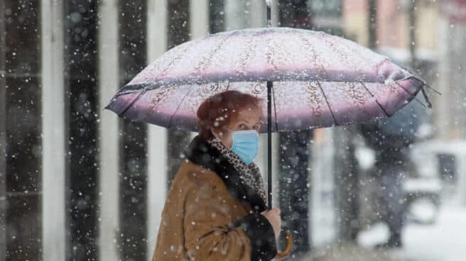 Una mujer se cubre de la nieve con un paraguas en Becerrea, en Lugo.