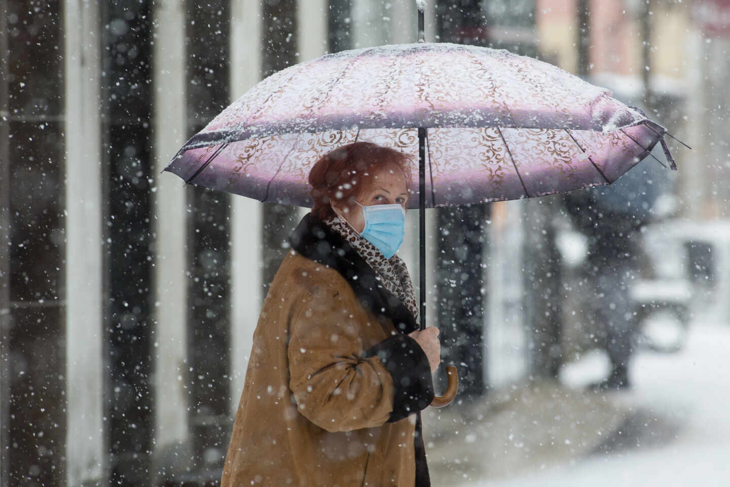 Una mujer se cubre de la nieve con un paraguas en Becerrea, en Lugo.