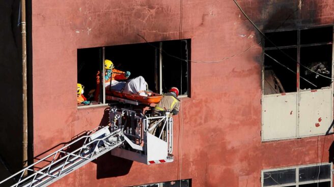 Los bomberos rescatan el cuerpo de uno de los fallecidos de la nave.