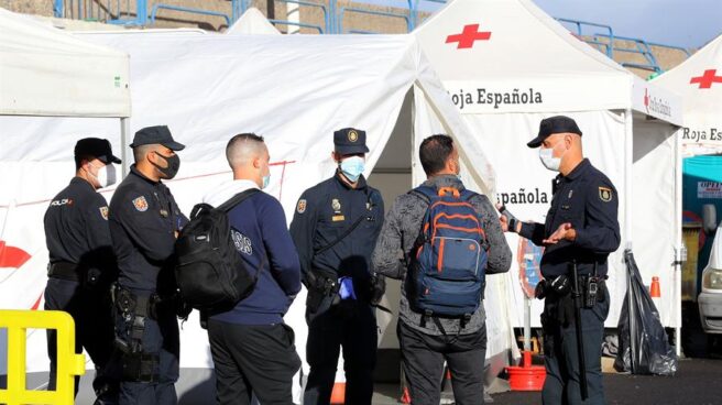 Policías junto a inmigrantes magrebíes en el muelle de Arguineguín.