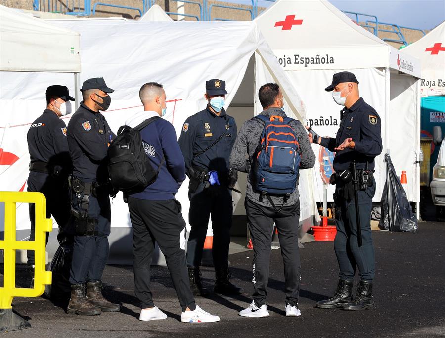 Policías junto a inmigrantes magrebíes en el muelle de Arguineguín.