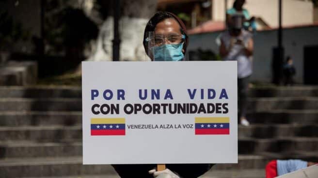 Un hombre sujeta un cartel con el lema 'Venezuela alza la voz'
