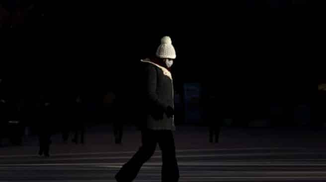 Una mujer con mascarilla camina por una calle de Valencia.