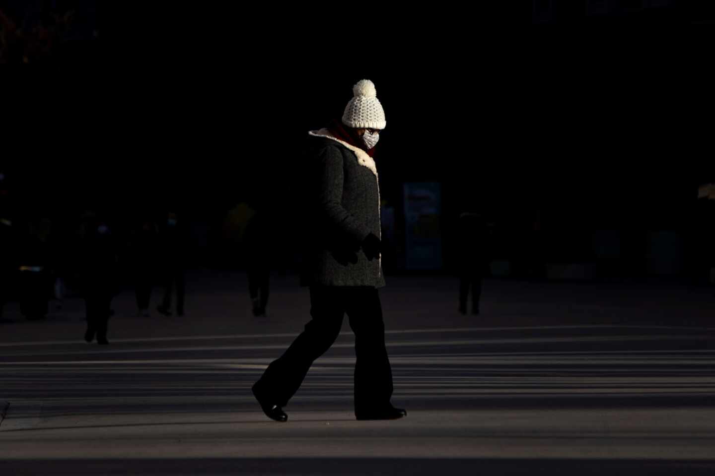 Una mujer con mascarilla camina por una calle de Valencia.