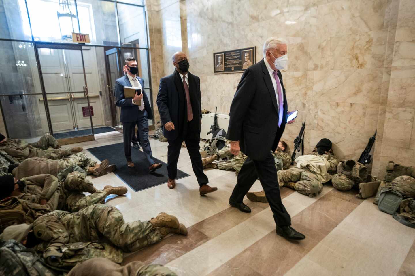 El líder de la mayoría, Steny Hoyer, pasa junto a miembros de la Guardia Nacional que intentan dormir dentro del Capitolio.