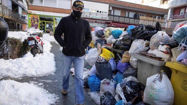 Un hombre camina junto a las bolsas de basura que se acumulan en las aceras y en los cubos situados en las calles de Madrid.