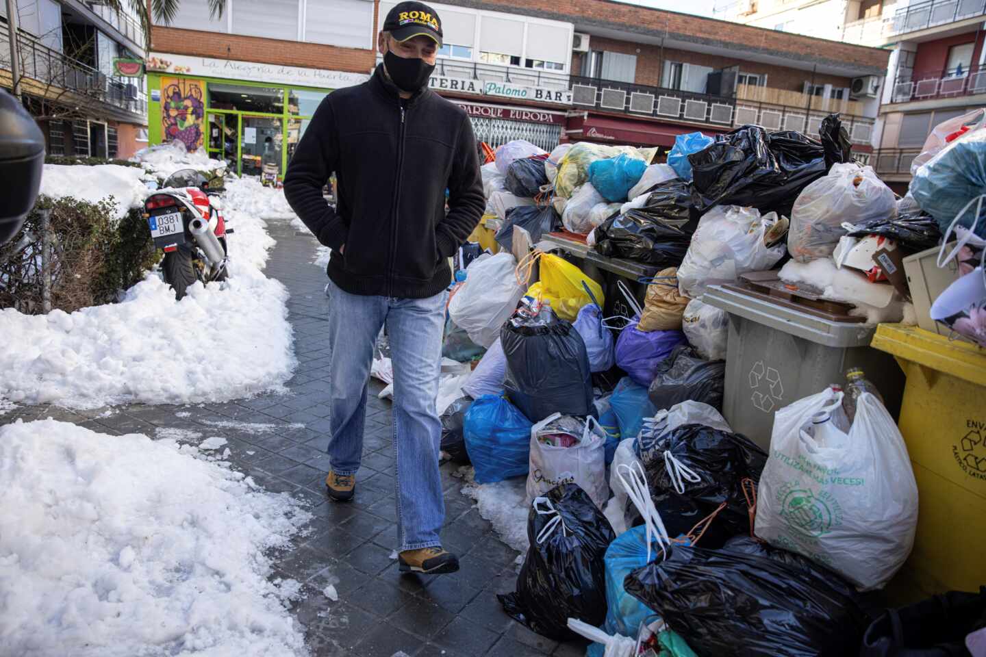 Un hombre camina junto a las bolsas de basura que se acumulan en las aceras y en los cubos situados en las calles de Madrid.