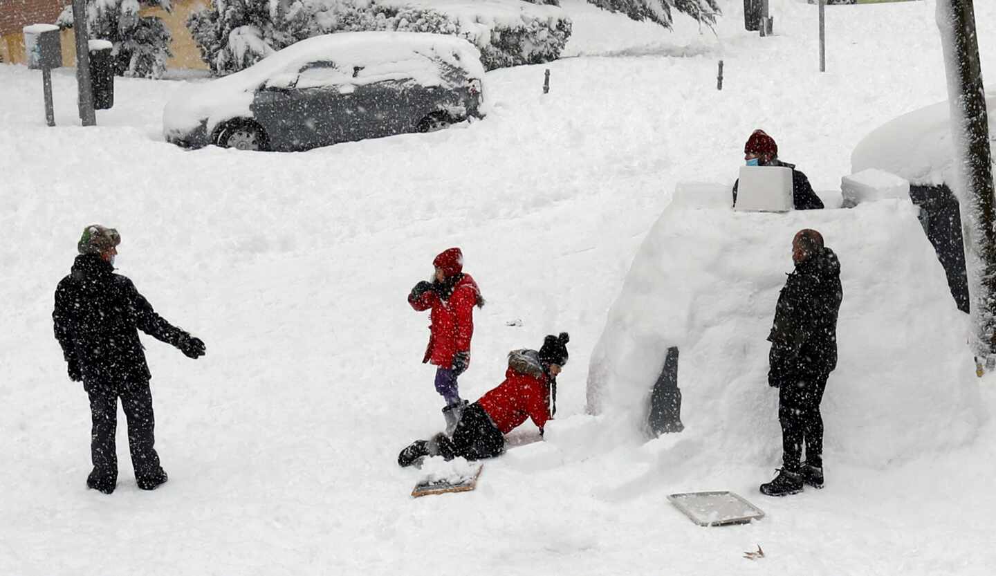 Varias personas construyen un iglú en una calle de Madrid.