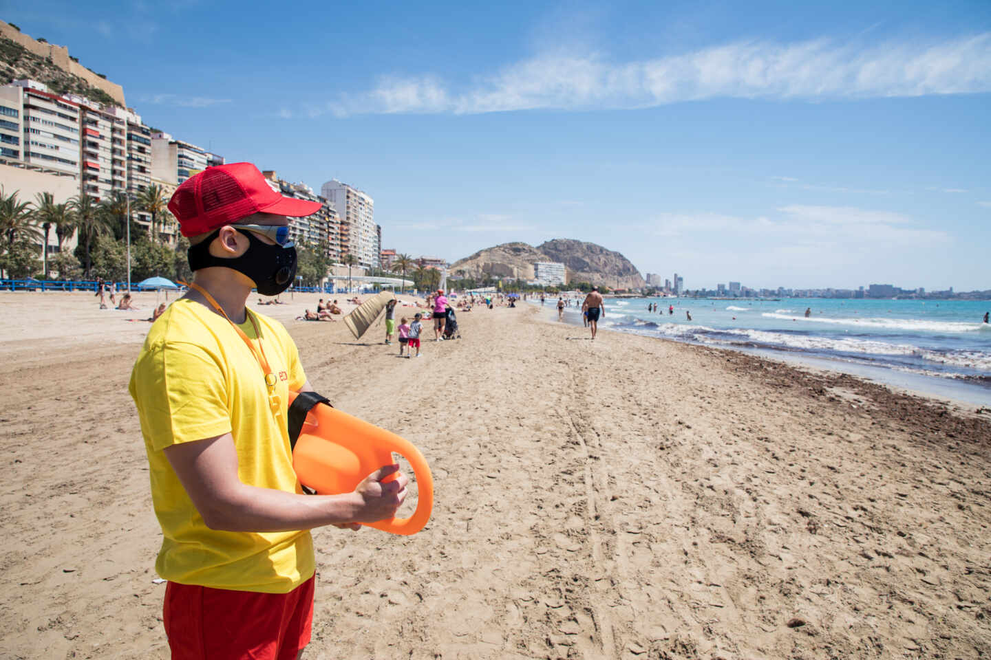 Un socorrista protegido con mascarilla vigila la Playa del Postiguet, en Alicante.