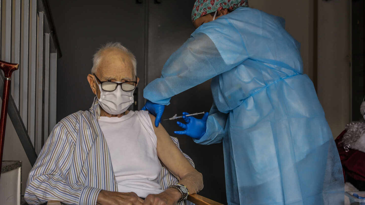 Un anciano es vacunado contra el coronavirus por una sanitaria en Valencia.