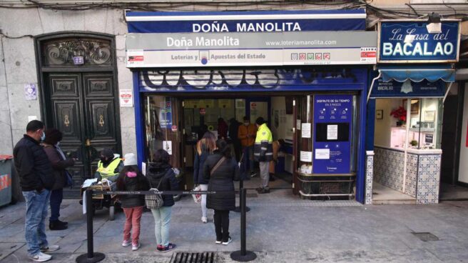 Varias personas hacen cola ante la administración de lotería Doña Manolita, en Madrid.