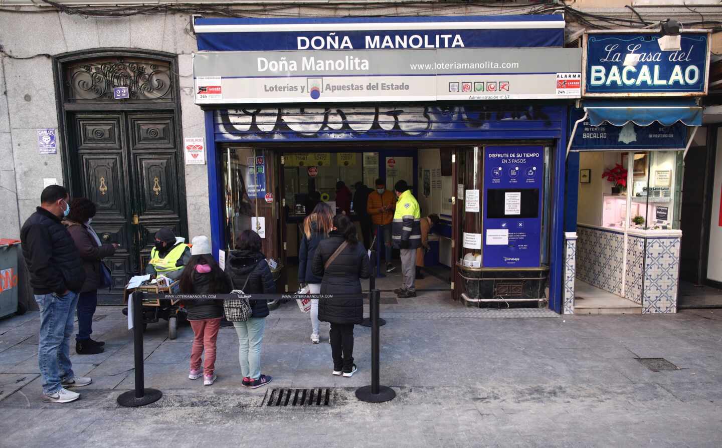 Varias personas hacen cola ante la administración de lotería Doña Manolita, en Madrid.