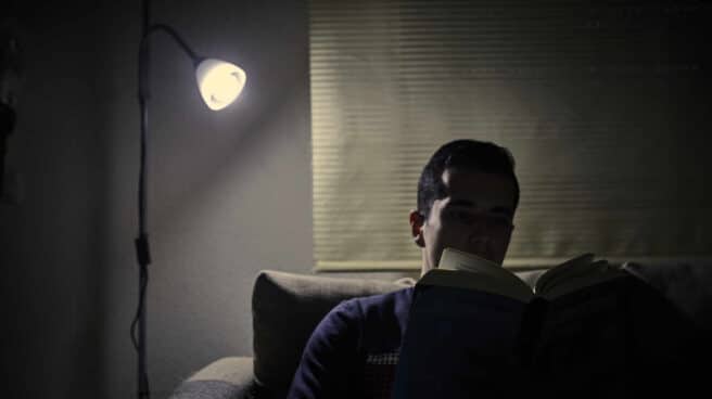 Un chico lee un libro bajo la luz de una lámpara en Madrid. Un chico lee un libro bajo la luz de una lámpara en Madrid.