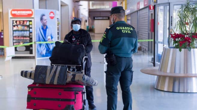 Agentes de la Guardia Civil y empleados de seguridad vigilan a los pasajeros en el interior del Aeropuerto de Ibiza.