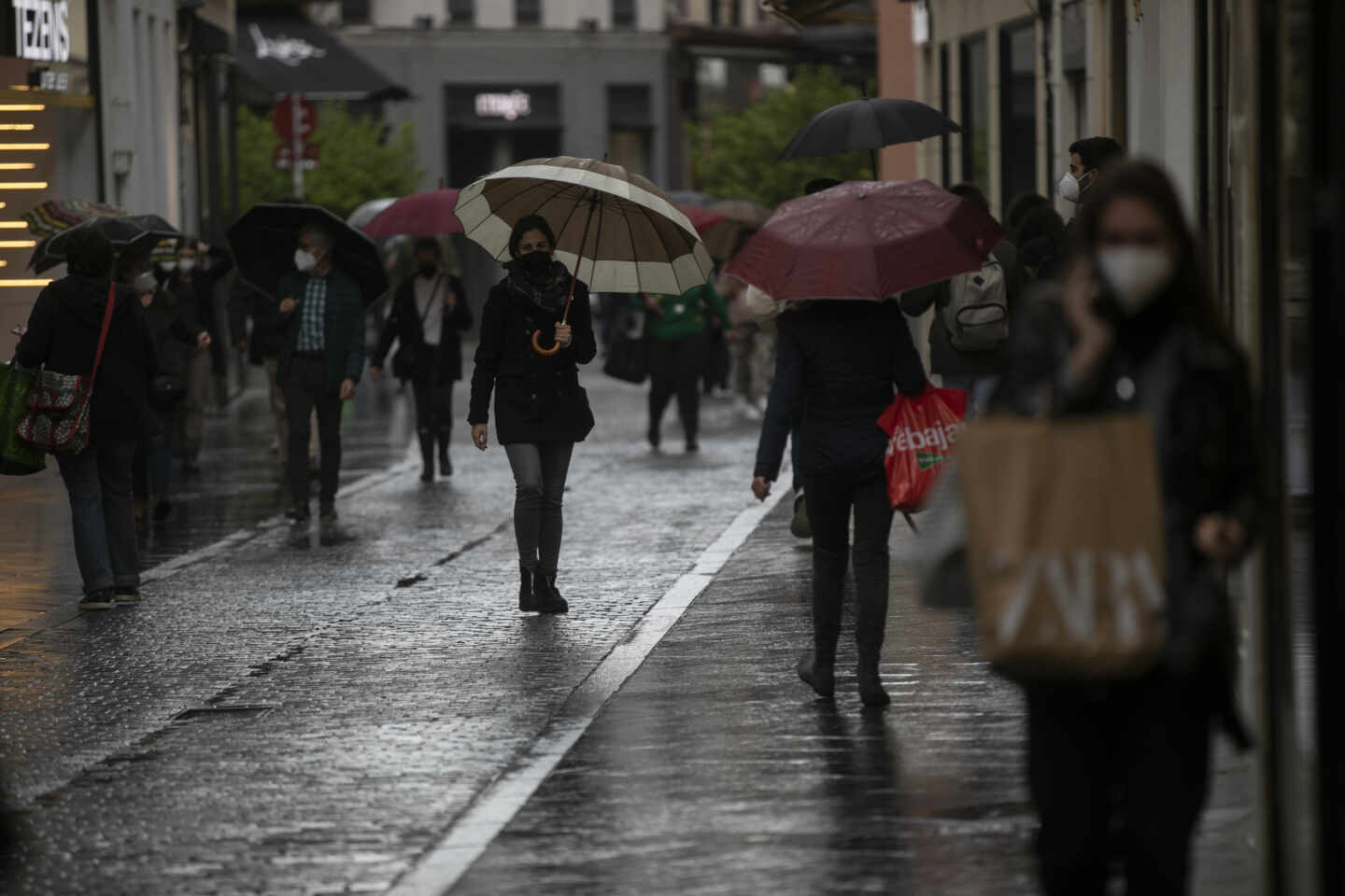 Varias personas con paraguas en una calle céntrica de Sevilla.