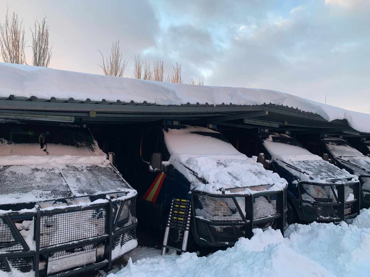 Vehículos de la UIP de Madrid, cubiertos de nieve este fin de semana en la base de Moratalaz (Madrid).