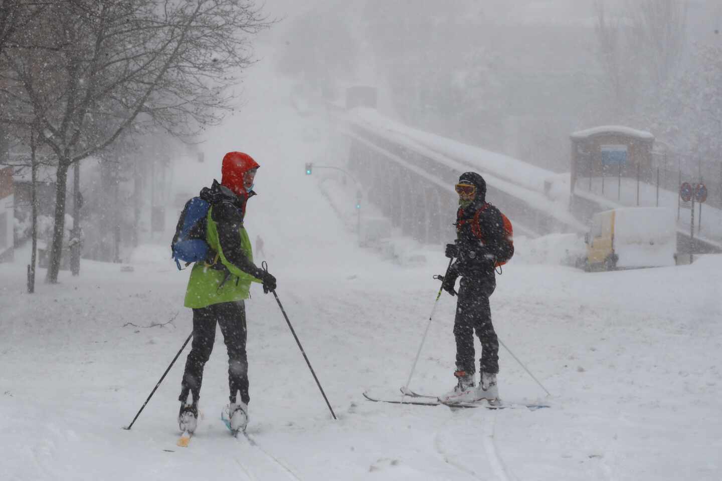 Viandantes esquían por una calle cubierta de nieve en Madrid.