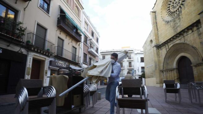 Un trabajador recoge el mobiliario de la terraza en Córdoba.