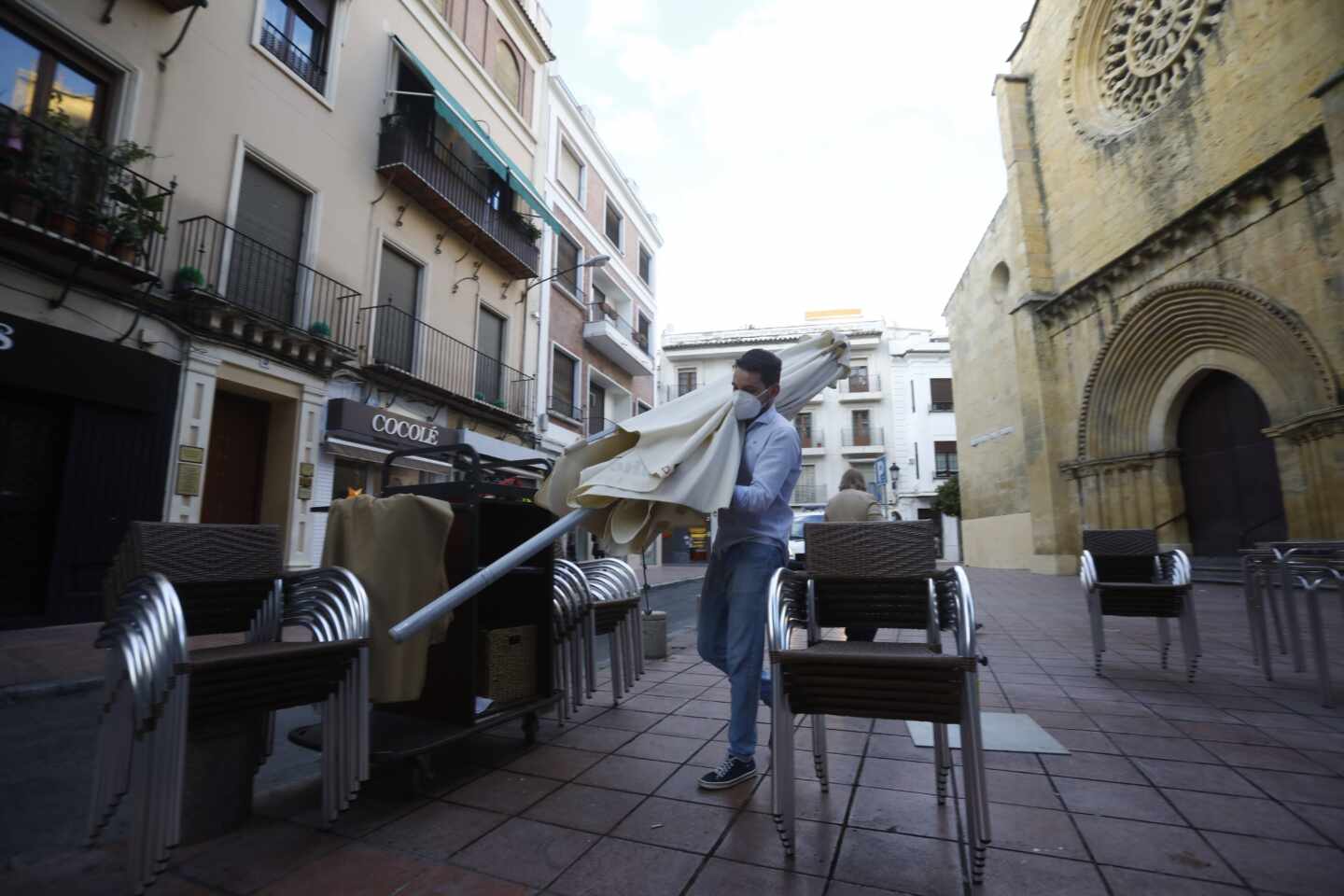 Un trabajador recoge el mobiliario de la terraza en Córdoba.
