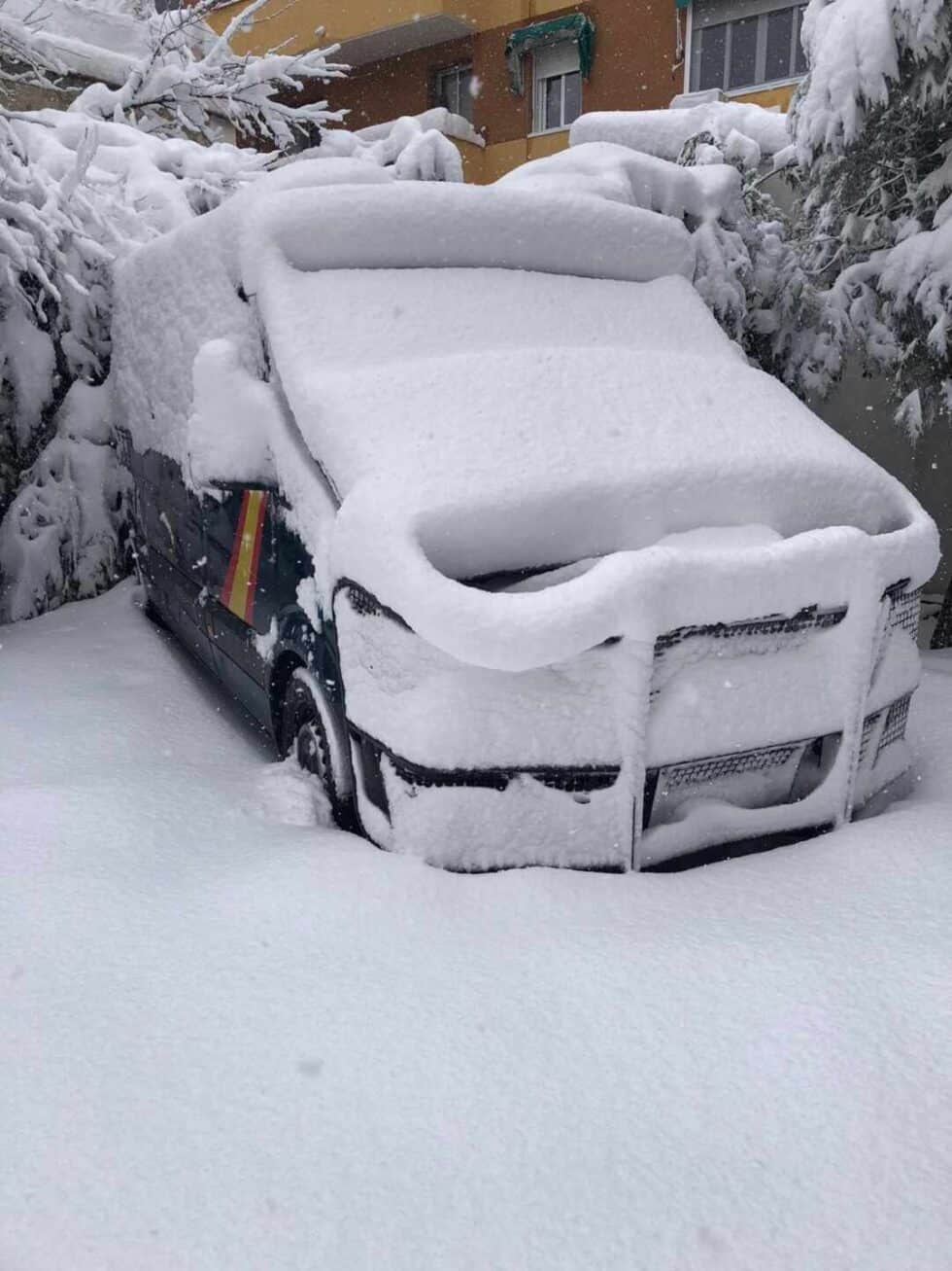 Furgones de la Policía Nacional cubiertos de nieve.