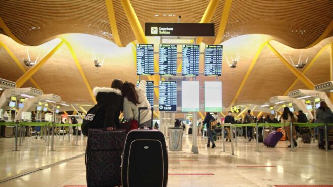 Más de 40.000 españoles decidieron emigrar durante los primeros seis meses de 2020 Dos viajeros señalando un panel de vuelo en la terminal T4 del Aeropuerto Adolfo Suárez Madrid-Barajas