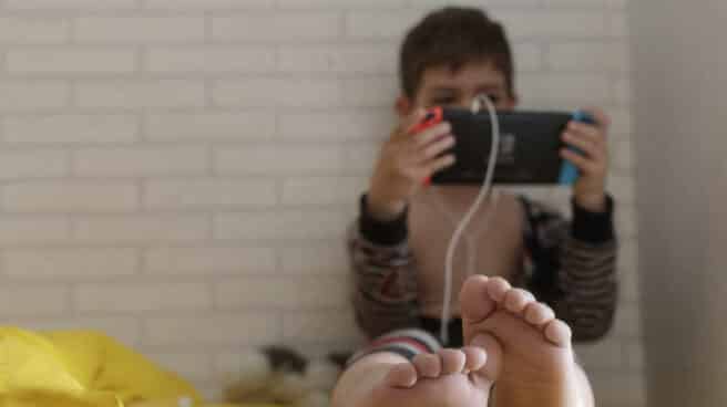 Un niño pequeño confinado juega con una tablet en su habitación