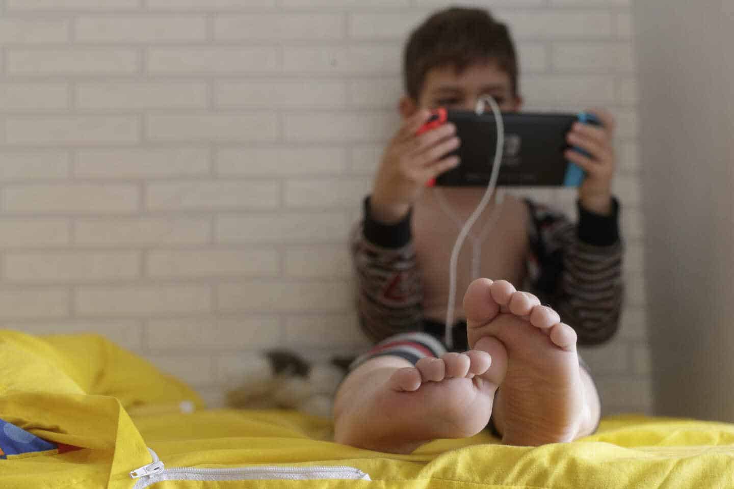 Un niño pequeño confinado juega con una tablet en su habitación