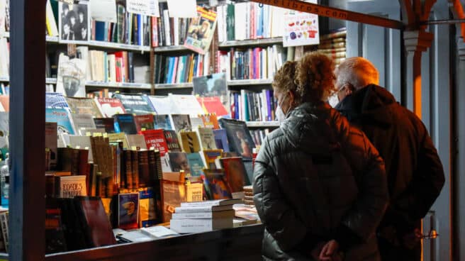 Dos personas ojean libros en un puesto callejero de libros