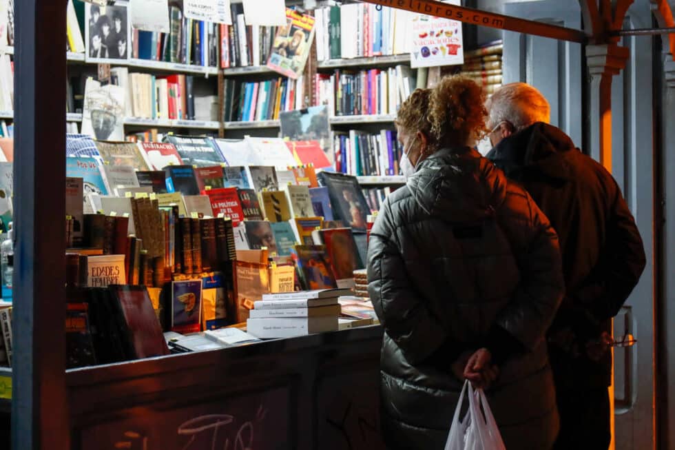 Dos personas ojean libros en un puesto callejero de libros