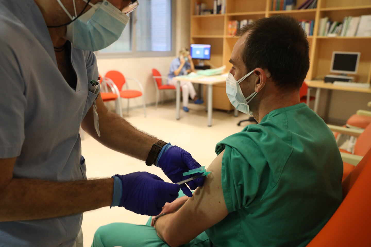 Una enfermera administra una vacuna contra el coronavirus a un enfermero