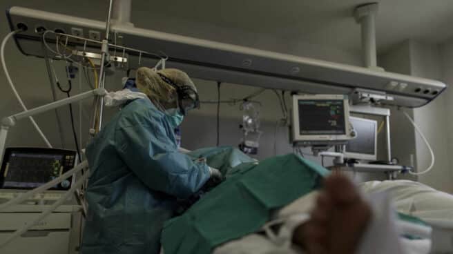 Personal sanitario totalmente protegido atiende a un paciente ingresado en la Unidad de Cuidados Intensivos del Hospital Infanta Sofía en San Sebastián de los Reyes (Madrid)
