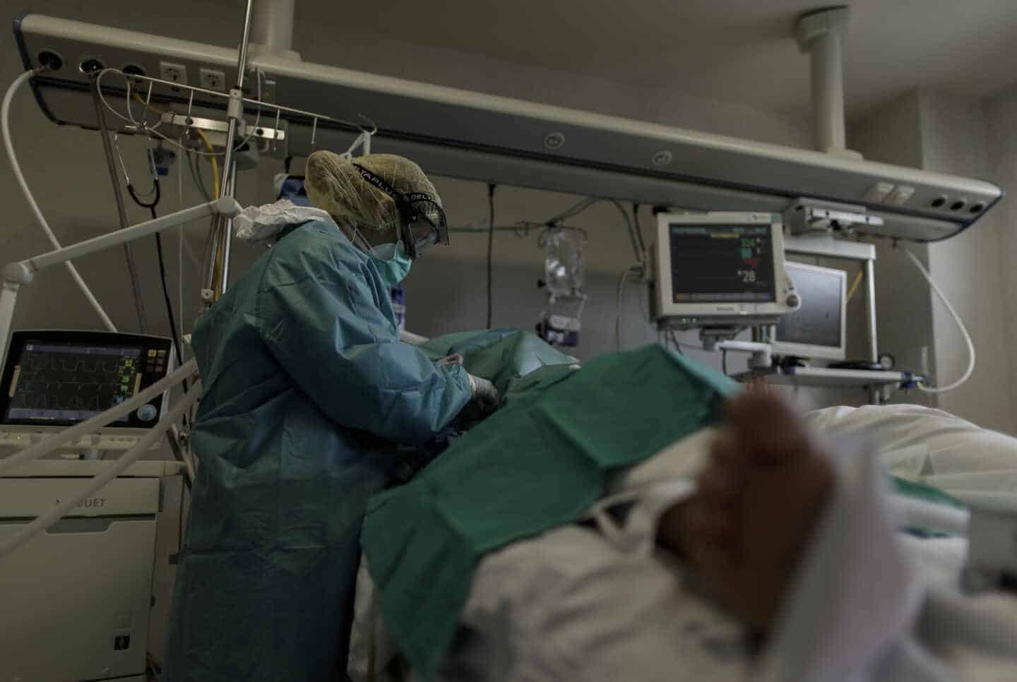 Personal sanitario totalmente protegido atiende a un paciente ingresado en la Unidad de Cuidados Intensivos del Hospital Infanta Sofía en San Sebastián de los Reyes (Madrid)