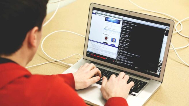 Un informe plantea cómo garantizar las pensiones de los trabajadores de plataformas digitales Un hombre escribe código en un ordenador portátil.