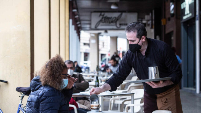 Un camarero sirve un café a una clienta en una cafetería durante el primer día de apertura de bares y restaurantes en Badajoz.