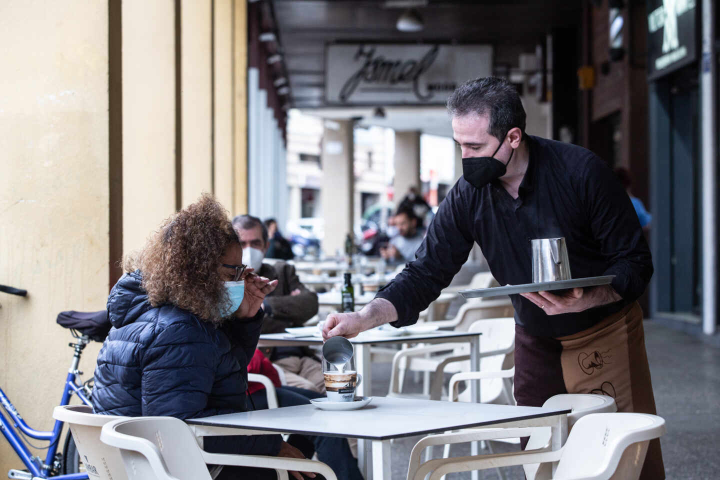 Un camarero sirve un café a una clienta en una cafetería durante el primer día de apertura de bares y restaurantes en Badajoz.