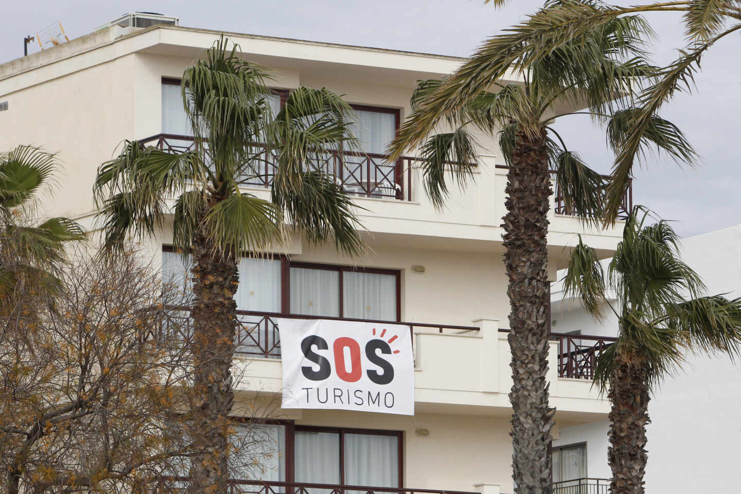 Un cartel colgado de un edificio donde se puede leer "SOS Turismo" en Baleares.