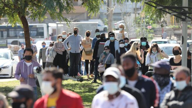 Extranjeros residentes en Israel hacen cola para recibir la vacuna de Pfizer.