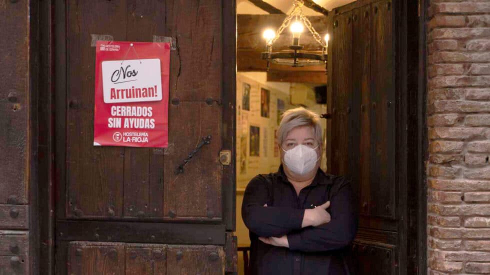 Imagen de una hostelera posa junto a un cartel de protesta por las restricciones en Logroño.