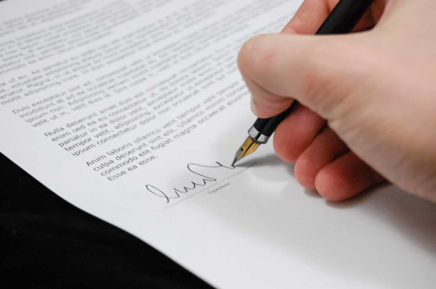 Una foto de archivo de una mano firmando un documento legal similar a la redacción de un testamento.