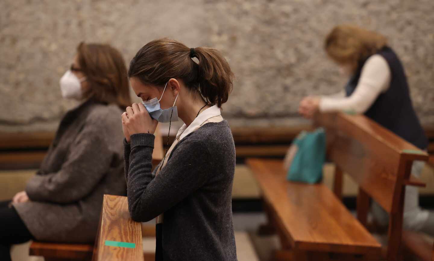 Una mujer reza durante la celebración de una Misa en la parroquia de Santa Elena (Madrid).