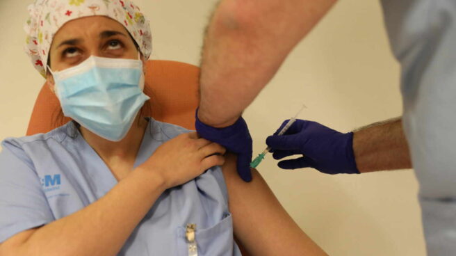 Una profesional sanitaria mira hacia arriba mientras recibe la vacuna del Covid.