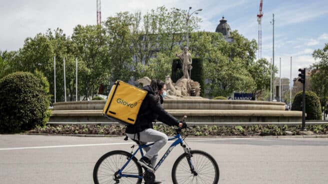 Una repartidora de Glovo en bicicleta por el centro de Madrid.