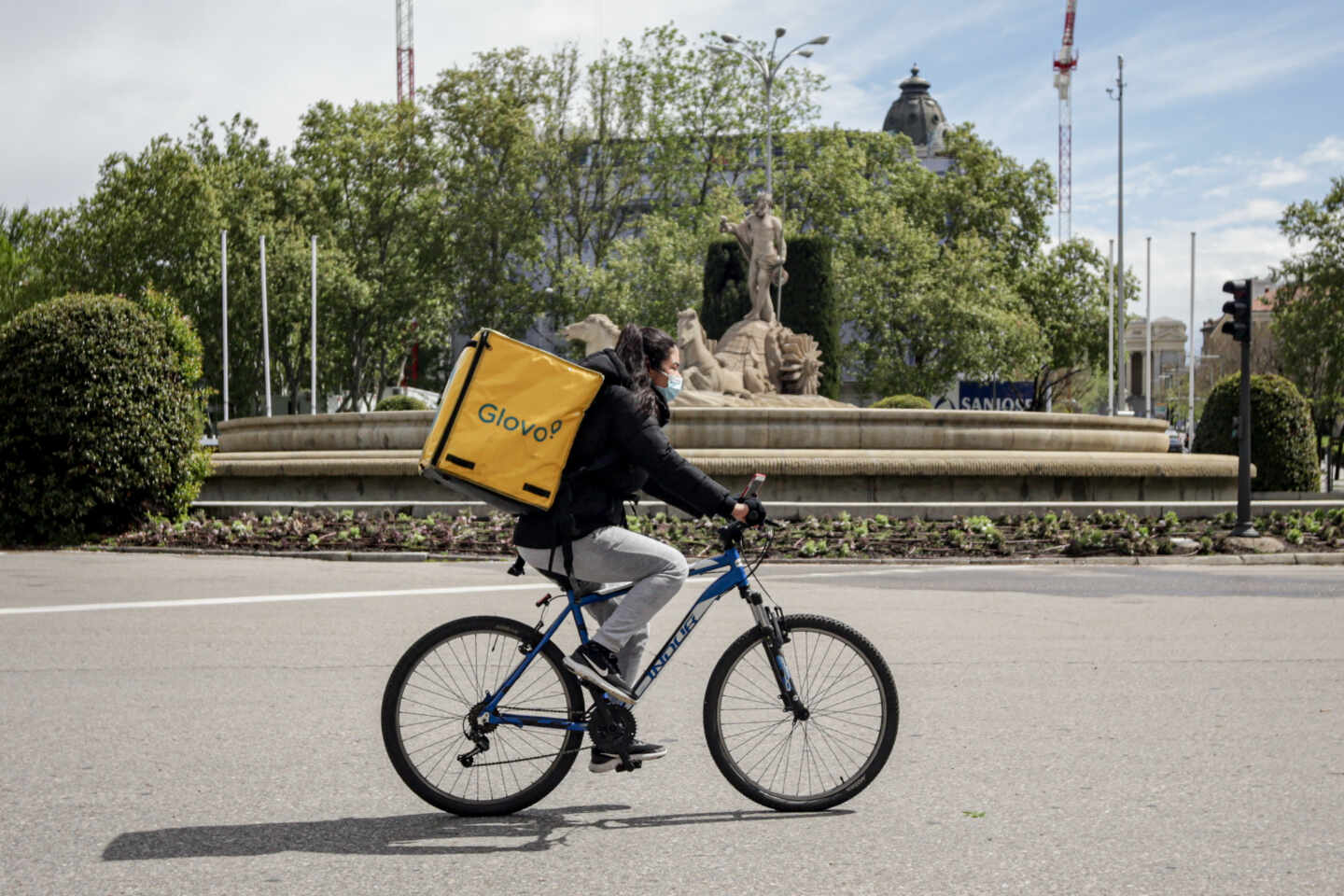 Una repartidora de Glovo en bicicleta por el centro de Madrid.