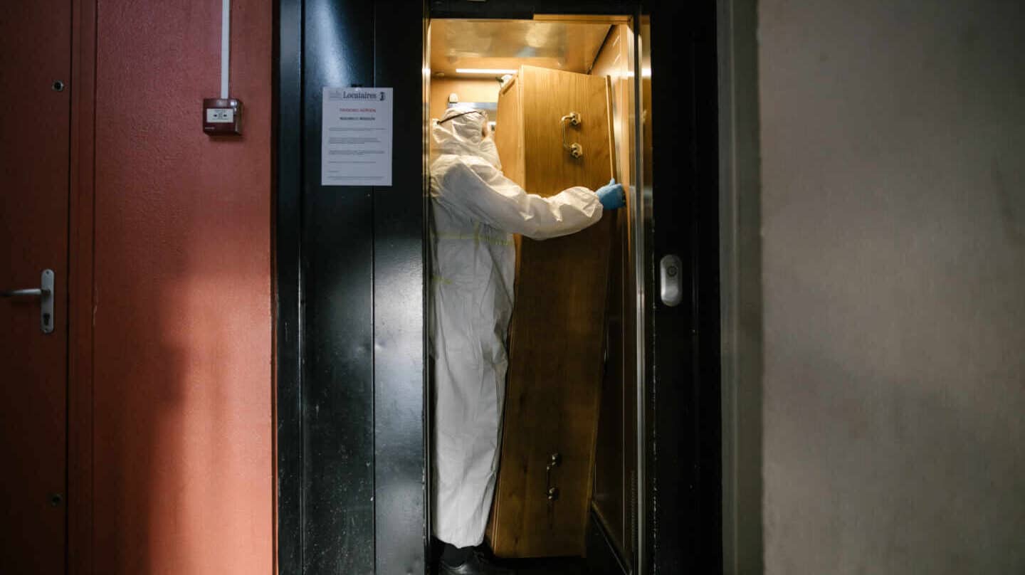 Un hombre porta un féretro en un ascensor.