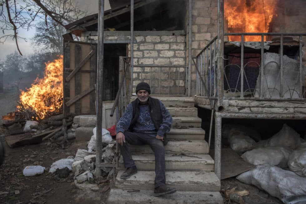 Un residente local de Areg se sienta frente a una casa en llamas en el pueblo de Karegakh, Nagorno-Karabakh. Algunos residentes quemaron sus casas antes de irse. Este conflicto ha pasado bastante desapercibido en un año marcado por la pandemia de Covid-19.