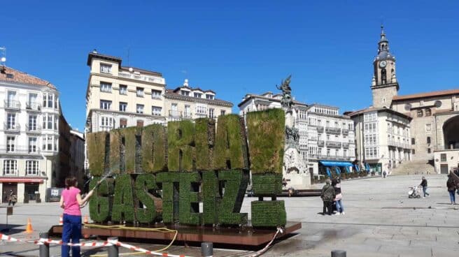 Una mujer riega el seto de Vitoria en la plaza de la Virgen Blanca de la capital alavesa.