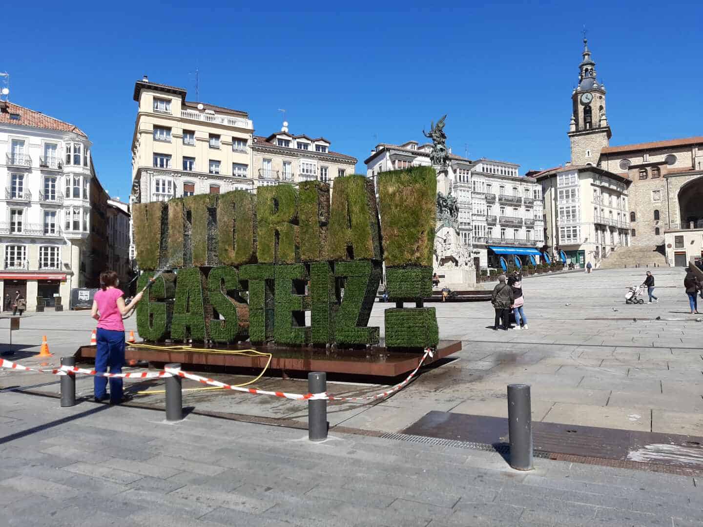 Una mujer riega el seto de Vitoria en la plaza de la Virgen Blanca de la capital alavesa.