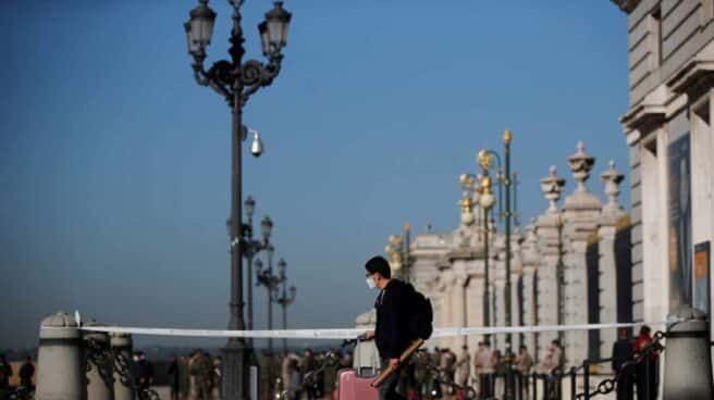 Polémica por las imágenes de franceses sin mascarilla y después del toque de queda en el centro de Madrid Un joven con su maleta pasa ante el Palacio Real de Madrid.